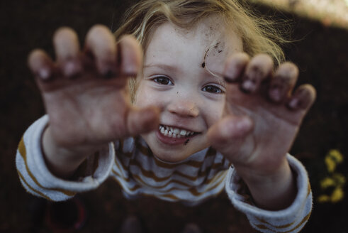 Hochformatiges Porträt eines glücklichen Mädchens, das auf einem Feld steht und gestikuliert - CAVF52705
