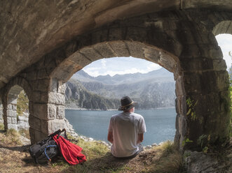 Italien, Wanderer unter Brücke sitzend, Blick auf den Lago di Salarno - LAF02139