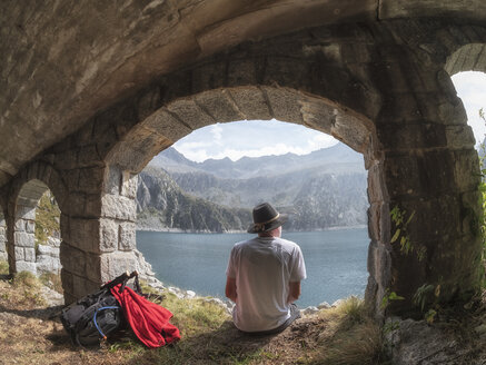 Italien, Wanderer unter Brücke sitzend, Blick auf den Lago di Salarno - LAF02139