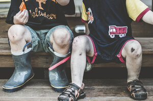 Niedriger Ausschnitt von Brüdern mit schmutzigen Beinen, die auf einer Holzbank sitzen - CAVF52764