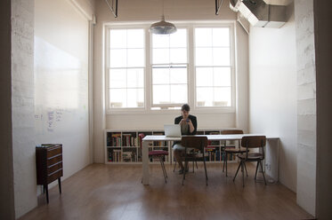 Businesswoman working while sitting against windows in new office - CAVF52785