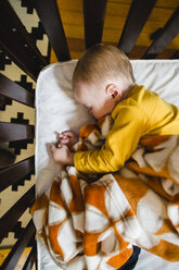 Draufsicht auf ein süßes Baby, das zu Hause in einem Kinderbett schläft - CAVF52901
