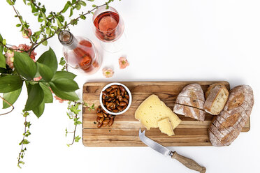 Hohe Winkel Ansicht von Brot mit Käse und Mandeln auf Schneidebrett von Wein über weißem Hintergrund - CAVF52915