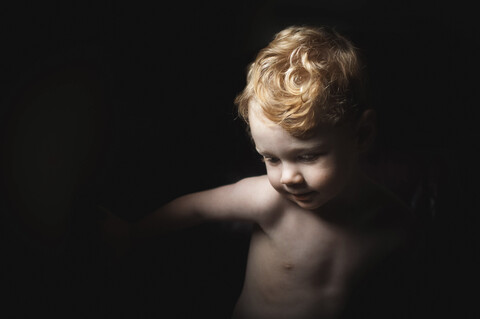 Nahaufnahme eines kleinen Jungen ohne Hemd in der Dunkelkammer zu Hause, lizenzfreies Stockfoto