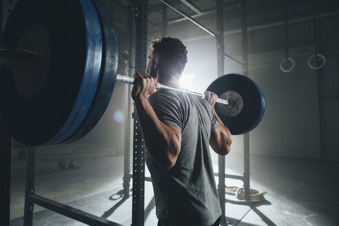 Seitenansicht eines männlichen Sportlers, der eine Langhantel im Fitnessstudio hebt - CAVF53004