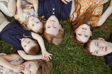High angle view of siblings lying on grassy field - CAVF53034