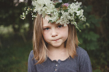 Close-up portrait of girl wearing flowers while standing at farm - CAVF53036