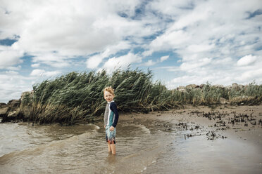 Porträt eines am Strand stehenden Jungen vor bewölktem Himmel - CAVF53061