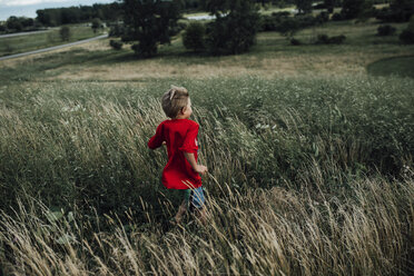 Rückansicht eines Jungen, der auf einem grasbewachsenen Feld läuft - CAVF53064