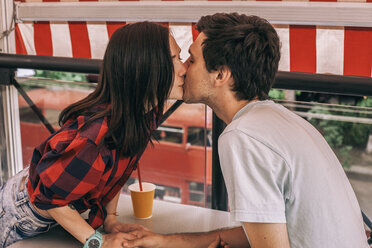 Seitenansicht eines jungen Paares, das sich im Café auf den Mund küsst - CAVF53068