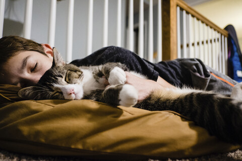 Boy with cat sleeping on bed at home stock photo