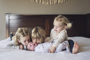 Liebevolle Schwestern mit einem kleinen Mädchen im Bett zu Hause - CAVF53117