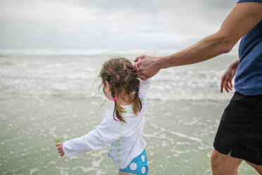 Daughter holding father's hand while walking in sea - CAVF53148