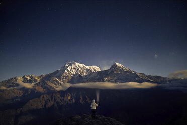 Rear view of tourist holding flashlight while standing on mountain against sky at night - CAVF53161