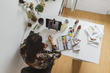 Illustratorin malt am Schreibtisch in einem Atelier mit digitalem Tablet, Draufsicht - AFVF01925