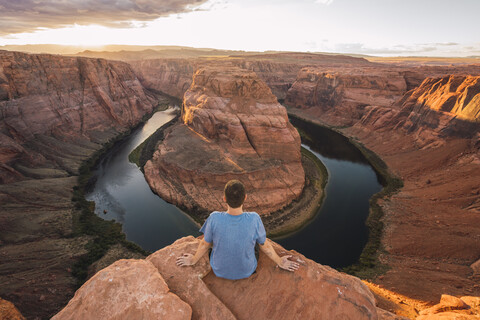 USA, Arizona, Colorado River, Horseshoe Bend, young man sitting on viewpoint stock photo