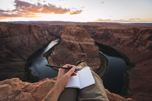 USA, Arizona, Colorado River, Horseshoe Bend, young man on viewpoint, notebook - KKAF02860