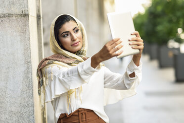 Spanien, Granada, junge muslimische Frau mit Hidschab, die im Freien einen digitalen Tablet-Computer benutzt - JSMF00550
