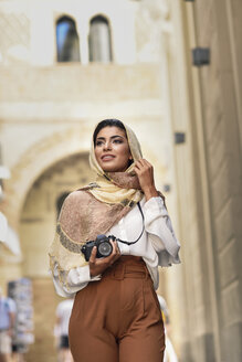 Spanien, Granada, junge arabische Touristin mit Hidschab, bei der Besichtigung der Stadt mit Kamera - JSMF00556