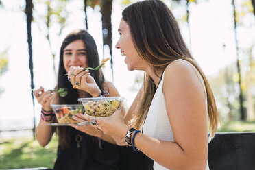 Freundinnen, die in einem Park sitzen und Salat essen - KKAF02867