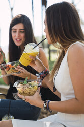 Freundinnen, die in einem Park sitzen, Salat essen und Saft trinken - KKAF02868