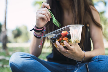 Young woman sitting in a park, eating salad - KKAF02874