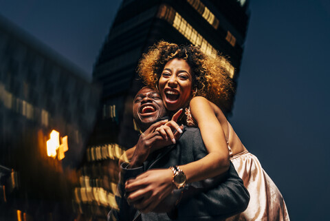 Lachendes junges Paar, das sich nachts in der Stadt amüsiert, lizenzfreies Stockfoto