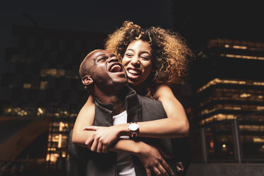 Lachendes junges Paar, das sich nachts in der Stadt amüsiert - OCMF00058