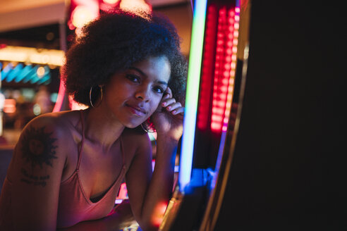 USA, Nevada, Las Vegas, Porträt einer jungen Frau an einem Spielautomaten in einem Kasino - KKAF02888