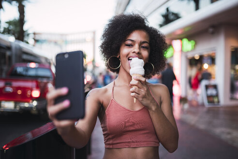 USA, Nevada, Las Vegas, happy young woman eating ice cream in the city taking a selfie - KKAF02904