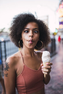 USA, Nevada, Las Vegas, portrait of young woman holding ice cream cone grimacing - KKAF02906