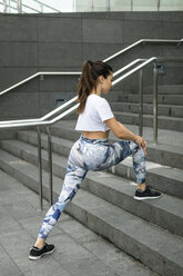 Young woman doing stretching exercise on stairs - FMGF00076