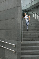 Young woman doing stretching exercise on stairs - FMGF00078