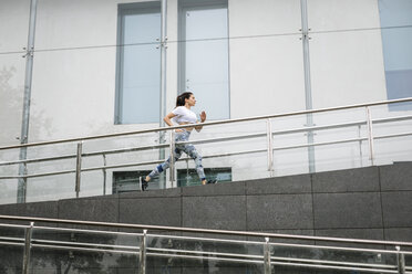 Junge Frau läuft an einem Gebäude in der Stadt entlang - FMGF00083
