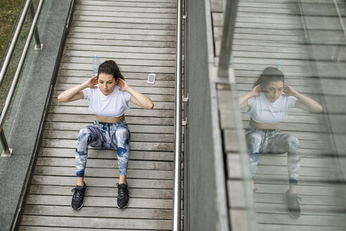 Junge Frau macht Situps auf einer Fußgängerbrücke - FMGF00086