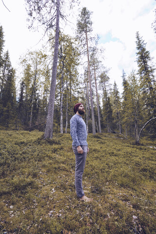 Schweden, Lappland, Mann steht auf einer Waldlichtung und entspannt sich, lizenzfreies Stockfoto