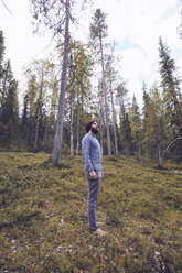 Schweden, Lappland, Mann steht auf einer Waldlichtung und entspannt sich - RSGF00040