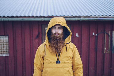 Sweden, Lapland, portrait of serious man with full beard wearing yellow windbreaker - RSGF00042