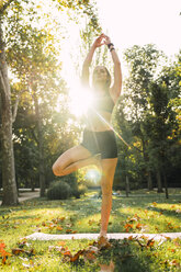 Fit junge Frau übt Yoga in einem Park - KKAF02937