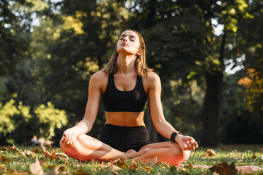 Fit junge Frau übt Yoga in einem Park - KKAF02941