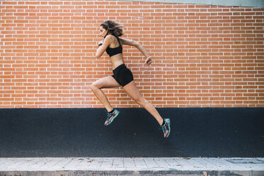 Fit young woman running an jumping in park - KKAF02946