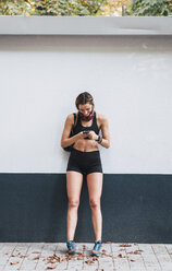 Fit young woman using smartphone after training - KKAF02949