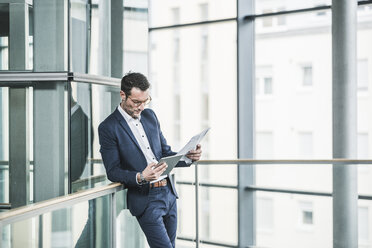 Businessman standing in office building, using digital tablet - UUF15802