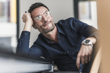 Älterer Mann sitzt im Büro, denkt nach und stützt den Kopf auf die Hand - UUF15807