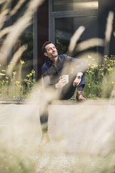 Businessman sitting outside, taking a break, drinking coffee - UUF15820