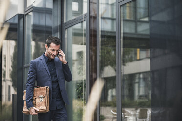 Businessman walking and talking on the phone - UUF15823