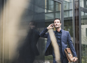 Businessman walking and talking on the phone - UUF15824