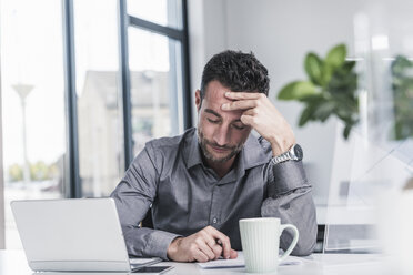 Müder Geschäftsmann sitzt im Büro - UUF15842