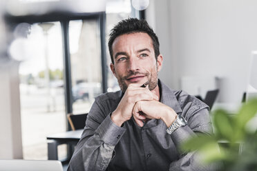 Businessman sitting in office, thinking - UUF15843