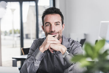 Portrait of a confident businessman, sitting in office - UUF15844